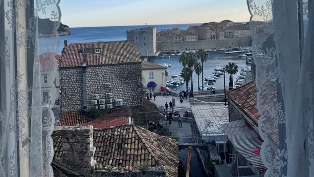 Un paisaje urbano costero con edificios históricos, un puerto y cielo despejado.