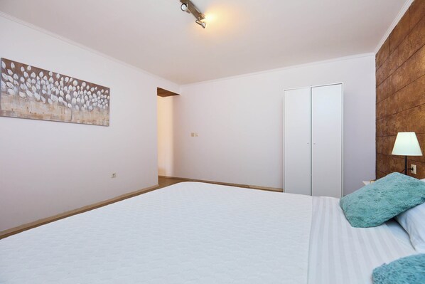 Un dormitorio con una cama grande, un cuadro en la pared, una pared de acento de madera y una puerta.