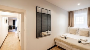 A bedroom with a bed, a wall-mounted mirror, and a view of a dining area. - Appartement Confort & Serenite 2bdr/4p (Cannes)