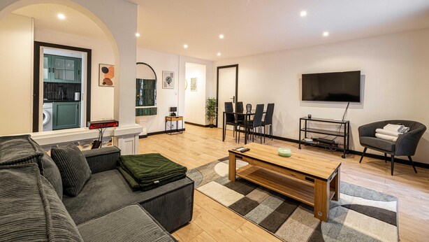 A modern living room with a sofa, a wooden coffee table, and a TV mounted on the wall. - Appartement Confort & Serenite 2bdr/4p (Cannes)