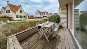 A wooden deck with a table and chairs, overlooking a row of houses with red-tiled roofs. - Apartment Near Albert Beach With Terrace (Knokke-Heist)