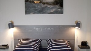 A bedroom with a bed, striped pillows, a wall-mounted picture, and bedside lamps.