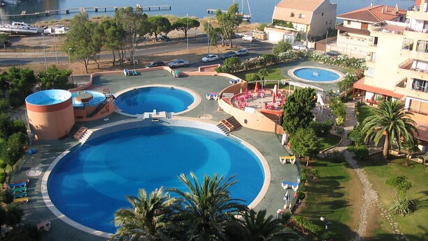 A resort with multiple swimming pools, a marina, and a view of the sea.