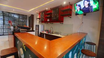Un área de bar moderna con mostrador de madera, taburetes y un televisor montado en la pared.