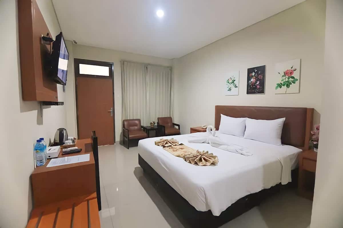 Une chambre d’hôtel avec un lit, un bureau et une chaise, une télévision et une fenêtre avec des rideaux.