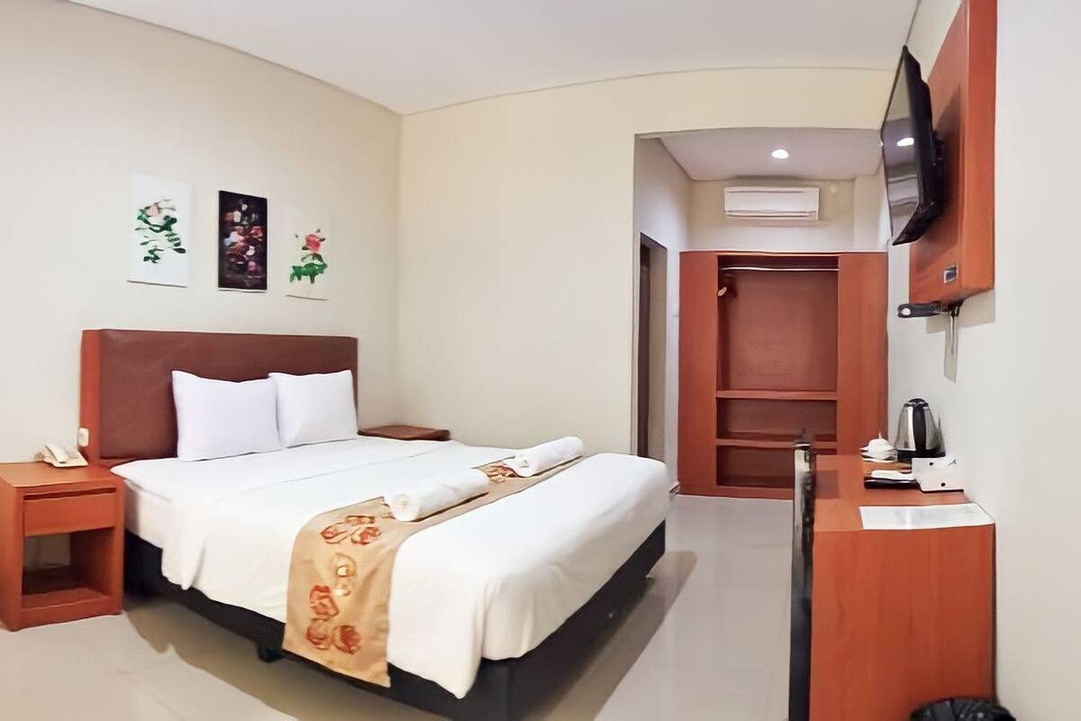 Une chambre d’hôtel comprenant un lit, une table de chevet, une chaise et un bureau avec une autre chaise.