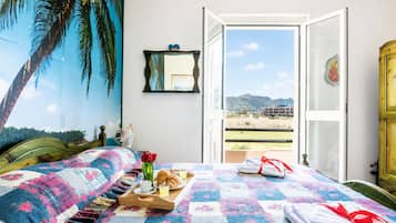 A room with a bed, a window, a door, and a view of the outdoors.