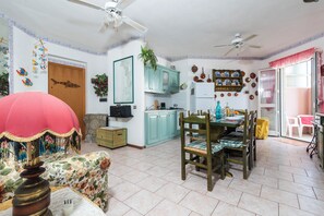 A spacious kitchen with teal cabinets, a dining area with wooden chairs, and a ceiling fan. - Residence 4 Colonne (Bosa)