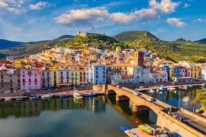 A coastal town with colorful buildings, a bridge, and boats docked along the waterfront. - Residence 4 Colonne (Bosa)
