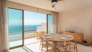 Un comedor moderno con una mesa redonda, sillas de madera y vista al océano.