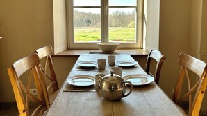 Mesa de comedor para cuatro con vistas a un campo verde a través de una ventana.
