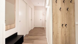Ein Flur mit Holzboden, weißen Wänden und einer Holztür mit Haken.
