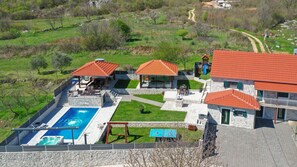 Ein Wohnhaus mit Swimmingpool, Außenbereich zum Sitzen und einem gepflasterten Weg.