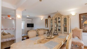 A spacious living room with a large wooden coffee table, a television, a cabinet with glass doors, and a comfortable seating area.