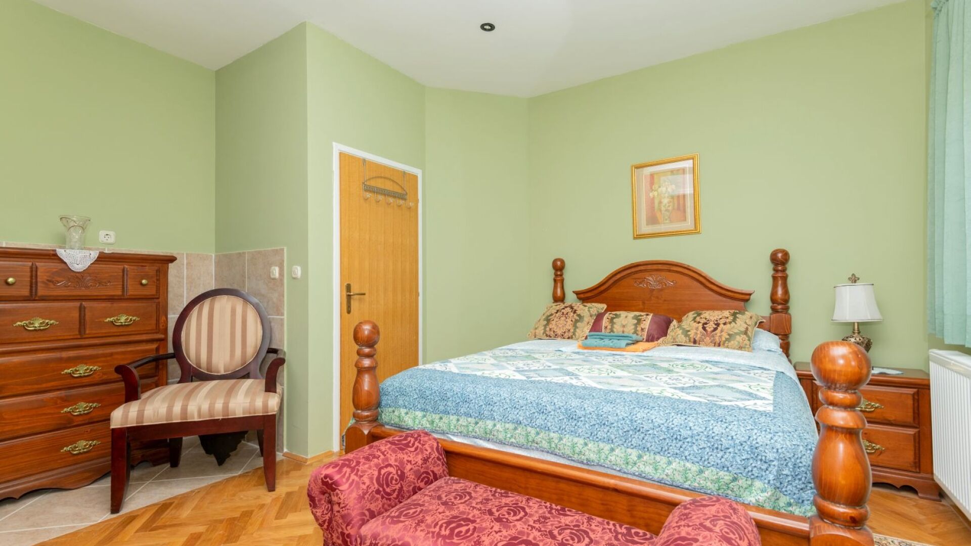 Une chambre à coucher avec un lit en bois, une chaise, une commode et une porte.