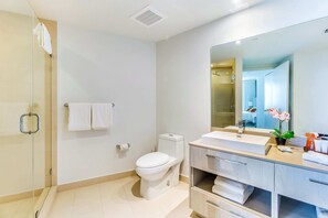 A modern bathroom with a glass shower enclosure, a white toilet, and a vanity with a large mirror. - Luxury Coastal Retreat with Pools and Ocean Breeze (Hollywood)