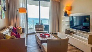 A modern hotel room with a balcony, a sofa, a coffee table, and a TV. - Luxury Coastal Retreat with Pools and Ocean Breeze (Hollywood)