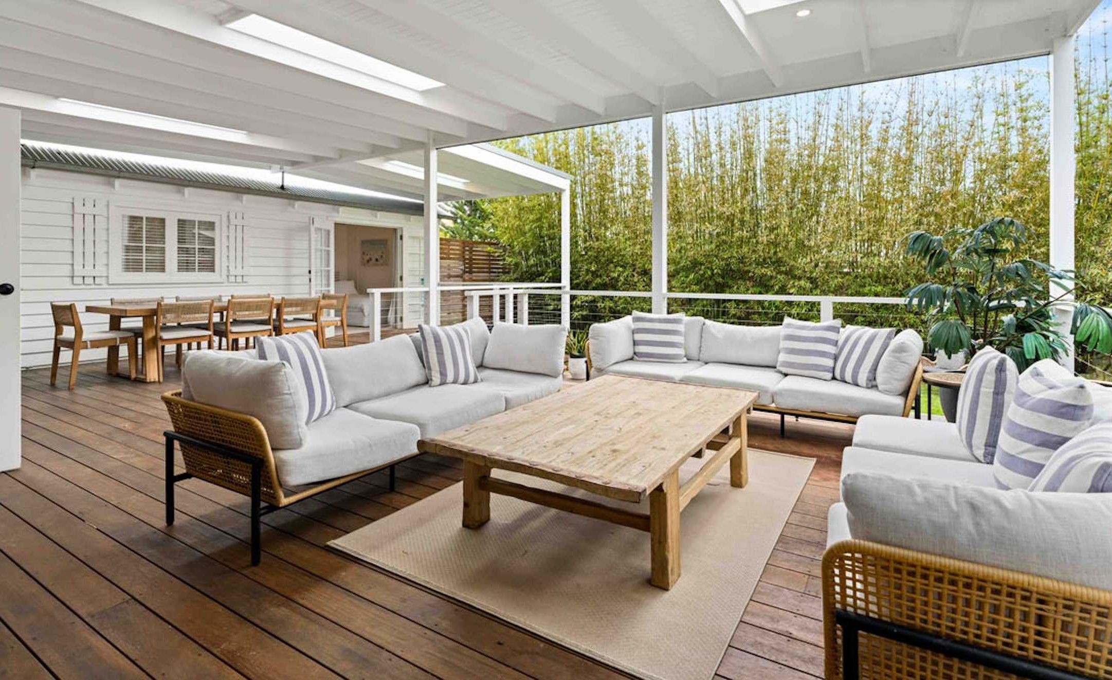 Un espace extérieur abrité, aménagé avec une table en bois, des canapés et des fauteuils.