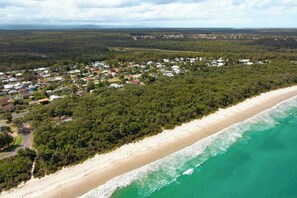 An aerial view of a coastal town with a beach and dense forest. - Conifer - Pet Friendly with Outdoor Spa (Callala Beach)