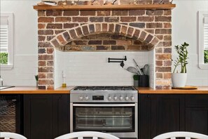 A kitchen with a brick oven, a stove, and dark cabinets. - Conifer - Pet Friendly with Outdoor Spa (Callala Beach)