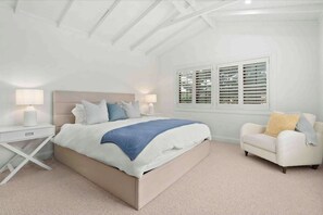 A bedroom with a bed, bedside tables, a nightstand, a window with shutters, and a chair. - Conifer - Pet Friendly with Outdoor Spa (Callala Beach)