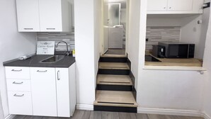 A compact kitchen with white cabinets, a black countertop, and a built-in microwave. - Casa Nina Seconda - Sanremo (Sanremo)