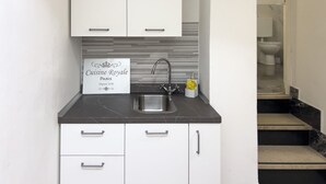 A modern kitchen with white cabinets, a black countertop, and a stainless steel sink. There is a sign on the wall that reads "Cuisine Royale Paris." - Casa Nina Seconda - Sanremo (Sanremo)