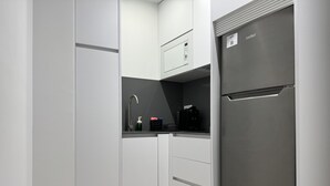 A compact kitchen with a built-in coffee maker, a sink, and a refrigerator.