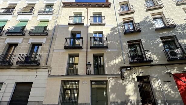 A multi-story building with balconies, a green door, and a red awning.