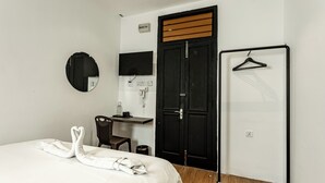 A hotel room with a bed, a desk, a chair, a mirror, a wardrobe, and a coat rack. - Earnest Hotel Georgetown (George Town)