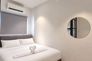 A hotel room with a bed, a round mirror, and an air conditioning unit. - Earnest Hotel Georgetown (George Town)