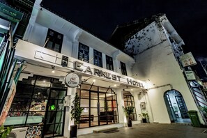 Un hôtel appelé «EARNEST HOTEL», avec une enseigne, de grandes fenêtres en verre et une entrée accueillante.