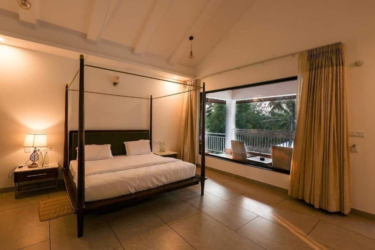 A four-poster bed in a room with a large window and a balcony.