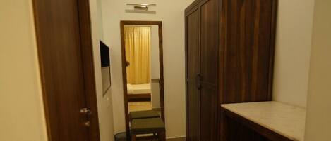A narrow hallway with a wooden door, a bench, a cabinet, and a small table.