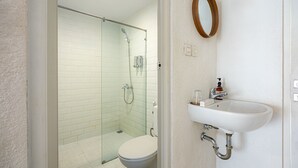 A bathroom with a toilet, a sink, a shower, and a mirror. - Cove Wong Village (Tumbak Bayuh)