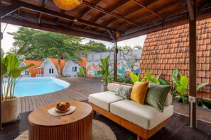 A covered outdoor area with a pool, a sofa, and potted plants. - Cove Wong Village (Tumbak Bayuh)