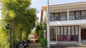 A building with a 'cove' sign, a covered outdoor seating area, and a row of parked motorcycles. - Cove Wong Village (Tumbak Bayuh)