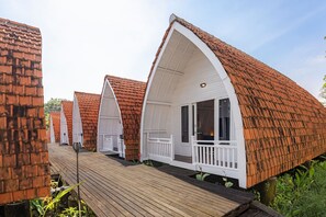 A row of bungalow-style cabins with pitched roofs and white railings. - Cove Wong Village (Tumbak Bayuh)