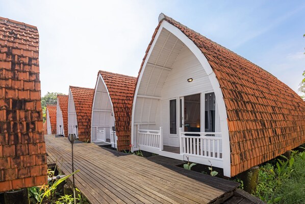 A row of bungalow-style cabins with pitched roofs and white railings. - Cove Wong Village (Tumbak Bayuh)