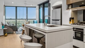 A modern kitchen with a central island, a built-in oven, and a large window offering a city view.