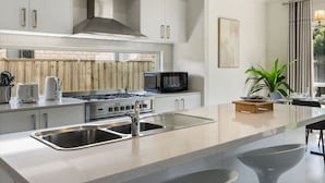 Una cocina moderna con una isla central, electrodomésticos de acero inoxidable y vistas al exterior.