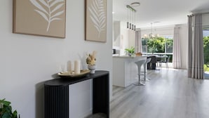 Una cocina moderna con una isla central, taburetes de bar y un comedor con vista a zonas verdes.