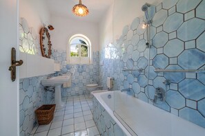A bathroom with a hexagonal tile pattern, a white sink, a toilet, and a bathtub.