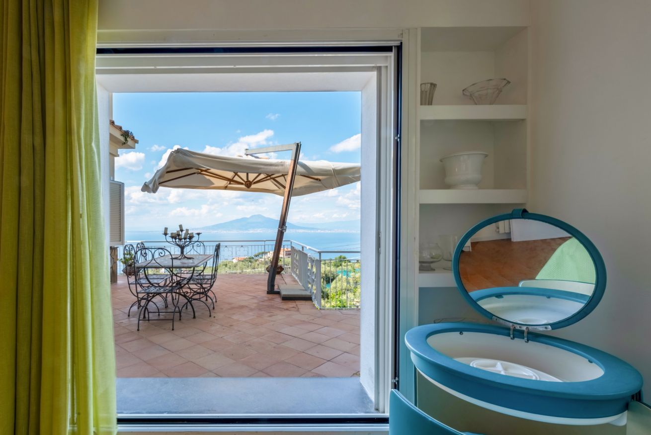 Una habitación con vistas a una terraza, una mesa con sillas y un inodoro azul.
