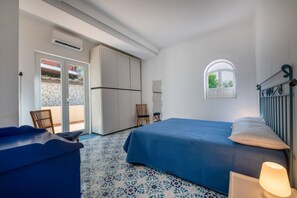 A bedroom with a bed, a chair, a desk, and a window.