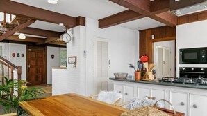 A kitchen with white cabinets, a wooden countertop, and a microwave.
