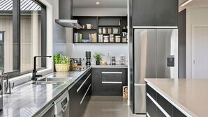 A modern kitchen with stainless steel appliances, a built-in oven, and a large window providing natural light. - Peaceful Luxury Retreat - with Spa Pool, a spacious, beautiful, private property with stunning views (Taupō)