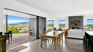 A modern living space with a dining area, a sofa, and a fireplace. - Peaceful Luxury Retreat - with Spa Pool, a spacious, beautiful, private property with stunning views (Taupō)