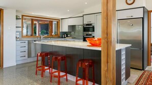 A modern kitchen with a central island, stainless steel appliances, and a large window. - Ultimate Retreat - Spacious with stunning lake views, natural mineral spa and underfloor heating. (Taupo)
