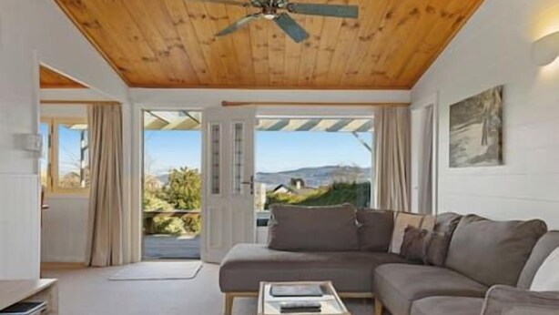 A modern living room with a wooden ceiling, a sofa, a coffee table, and a view through a glass door.